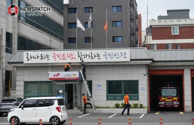 수원남부소방서 지만119안전센터 입구 처마 방수 보수작업에서 안전모를 미착용한 상태로 사다리 작업하는 모습  [사진=ⓒ뉴스패치]